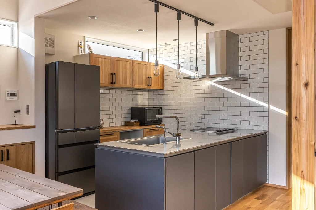 タイルのアクセントウォールとステンレストップに木目を合わせた、ナチュラルでスタイリッシュな対面キッチン。