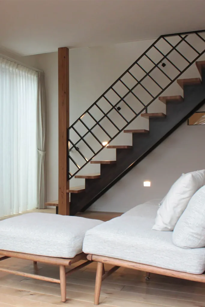 踏板とささら桁で色味の異なる木材を使用した階段。斜めのデザインの手すりが個性的。