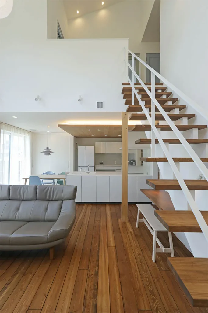 踏板は床材の茶色、手すりやささら桁は壁やキッチンの白と合わせて、まとまりと開放感のある空間に。