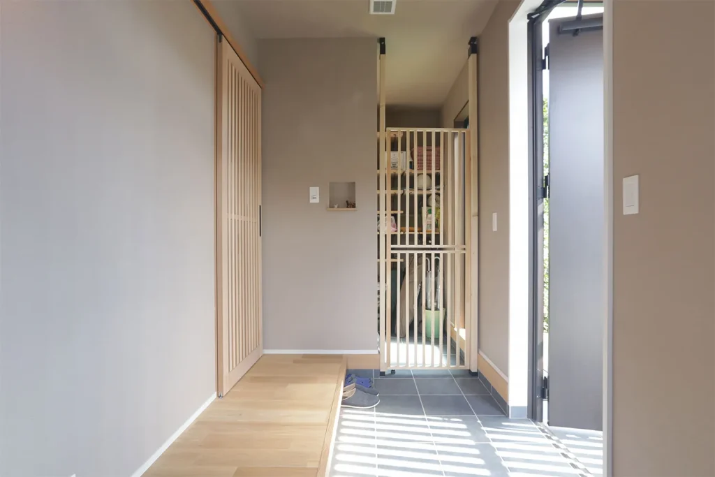 格子の引き戸とグレーのクロスが和の雰囲気を醸し出す玄関。ペットの脱走防止柵も造作なら空間に馴染む。